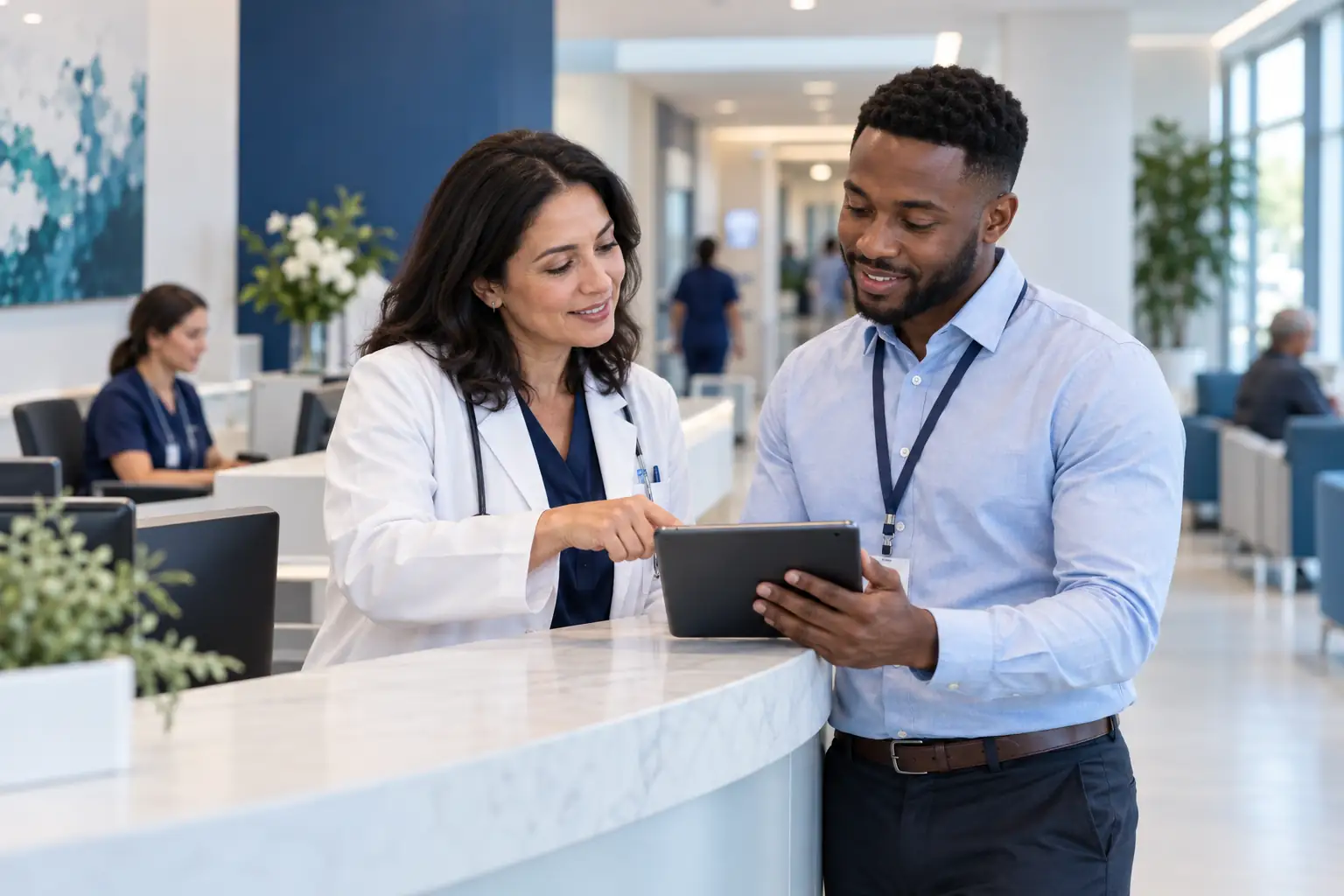 Healthcare administrator and colleague reviewing a registration tablet in a hospital reception